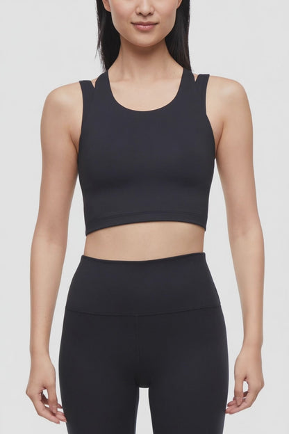 Video view of woman wearing a black sports bra and black leggings on a white background. 