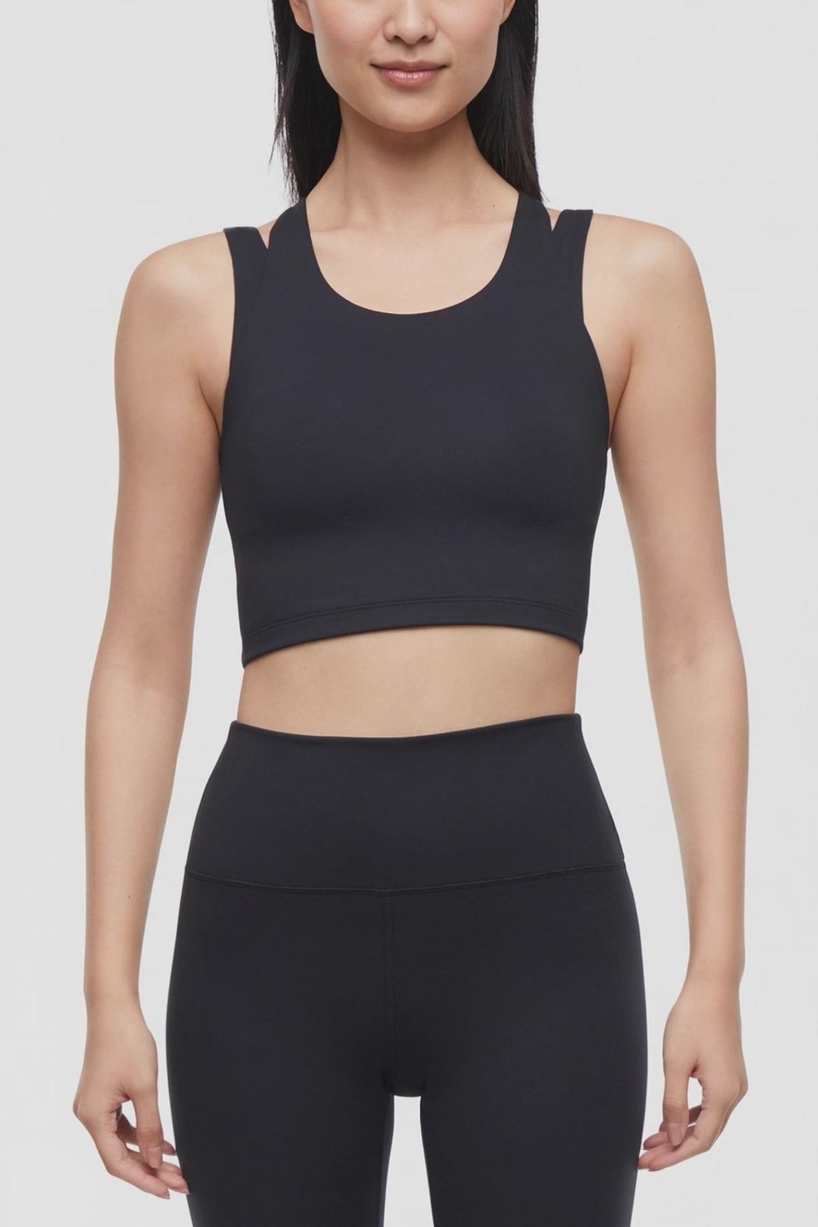 Video view of woman wearing a black sports bra and black leggings on a white background. #color_black