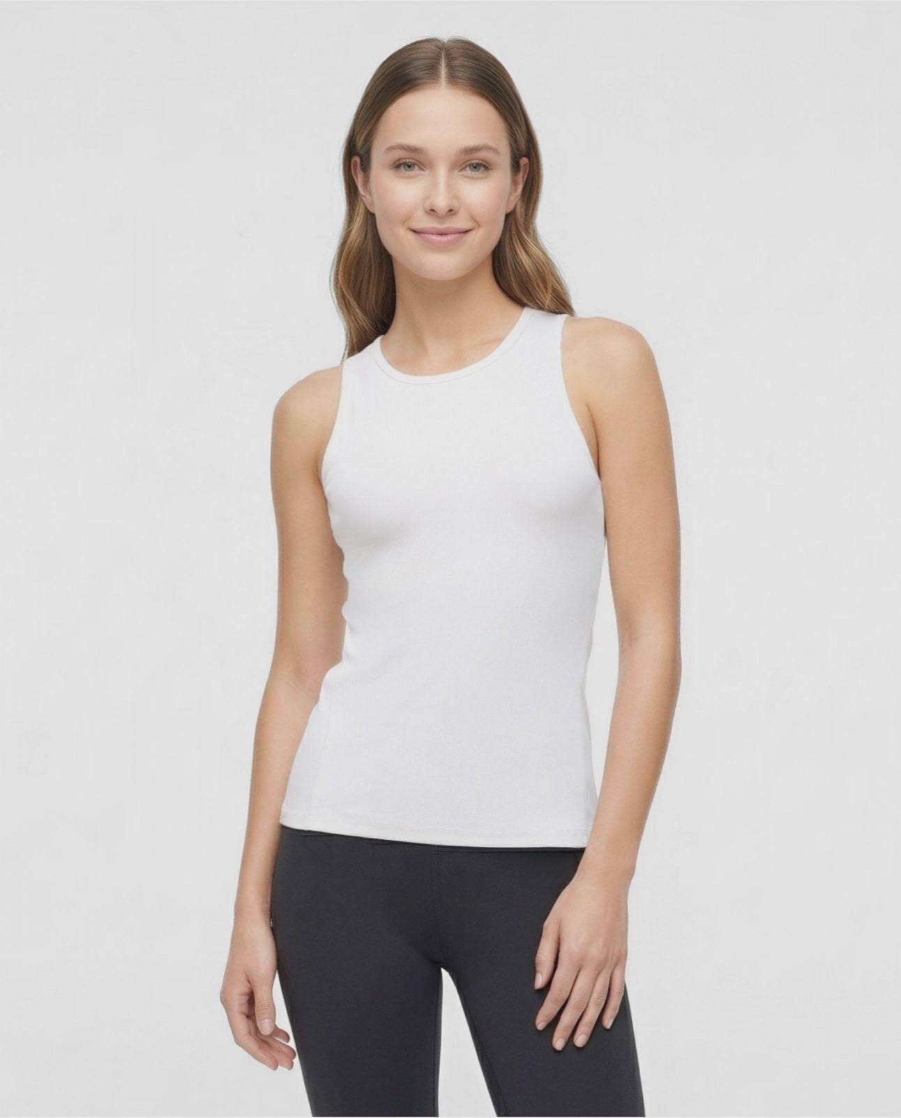 VIDEO View of woman wearing a white sleeveless top and black leggings on a light gray background. #color_sugar-swizzle