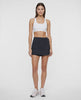 Video of woman wearing a black skort with waist clasp and white sneakers on a white background. #color_black