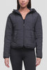 Video of a woman wearing a dark gray quilted puffer jacket with a hood and front zipper, paired with black leggings, shown against a light gray studio background. #color_phantom