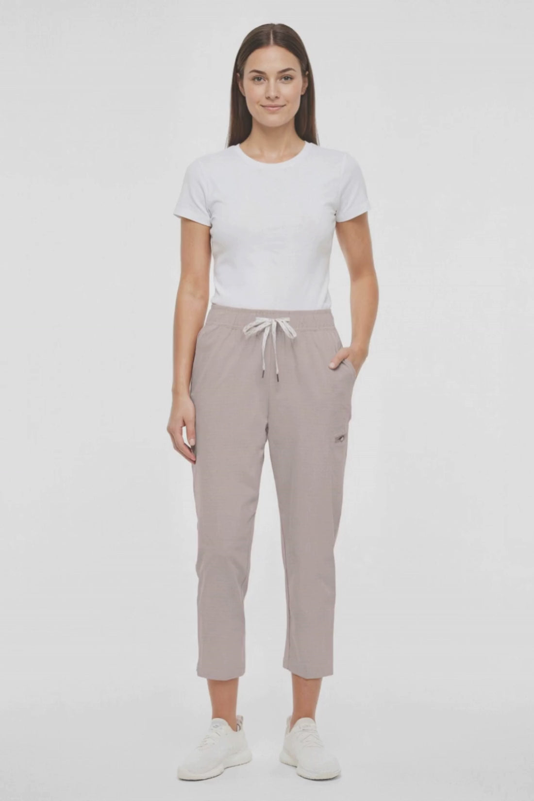Video view of beige pants worn by a woman with white drawstring waist on a white background. 